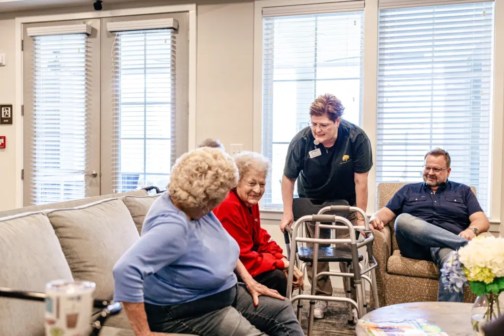 A team member and older adults gathered for conversation in a lounge